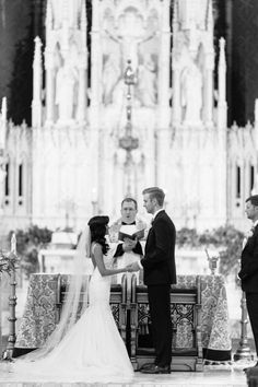 a bride and groom standing at the alter during their wedding ceremony in front of an ornate cathedral