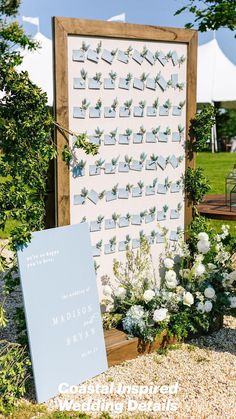 an outdoor ceremony with flowers and a sign for guests to place their names on the wall