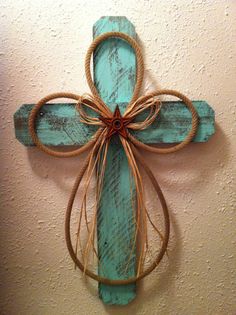 a cross made out of wood and rope hanging on the wall next to a wall