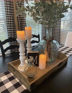 a wooden tray with candles on top of it next to a vase filled with flowers