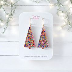 Christmas tree earrings, colorful rainbow glitter holiday jewelry, festive jewelry, acrylic earrings with a glitter rainbow pattern, perfect gift for her, mom, or friend. These vibrant earrings measure between 2.20 to 1.90 inches in length and 0.90 inch wide, adding a playful yet elegant touch to your festive outfits. Ideal for accessorizing during the holiday season or as a unique gift, these earrings feature high-quality stainless steel findings for sensitive ears. Whether you're attending a Christmas party or looking for a thoughtful holiday present, these earrings are a stylish choice. Arriving in a gift bag accompanied by a polishing cloth, these earrings are carefully packaged in a shipping box to guarantee their safe journey to you. Should you have any inquiries, please do not hesit Colorful Beads Earrings For Christmas Gift, Holiday Multicolor Handmade Earrings, Colorful Beads Christmas Earrings Gift, Beaded Christmas Earrings, Acrylic Christmas Earrings, Multicolor Christmas Earrings, Christmas Party Gift, Winter Earrings, Christmas Tree Earrings