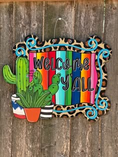 a wooden sign that says welcome y'all with a cactus and cacti