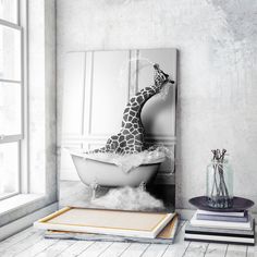 a giraffe sitting in a bathtub next to some books and a vase