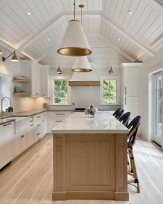 a large kitchen with an island in the middle and two stools at the end