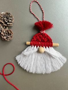 an ornament made out of yarn with pine cones on the table next to it