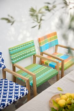 three chairs sitting next to each other on top of a white table with blue and green patterned cushions