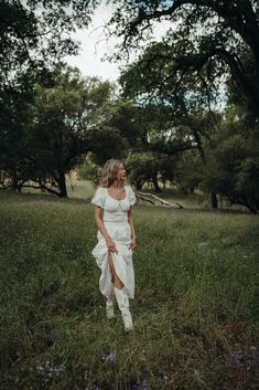 a woman in a white dress is standing in the grass