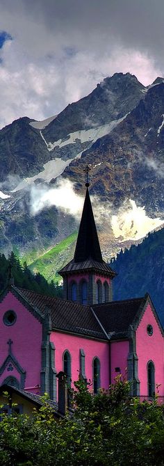 a pink church with a steeple in the mountains