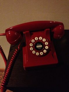 an old red telephone sitting on top of a table