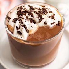 a close up of a cup of hot chocolate with whipped cream and chocolate shavings