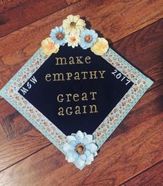 a black graduation cap with flowers on it that says make empathy great again