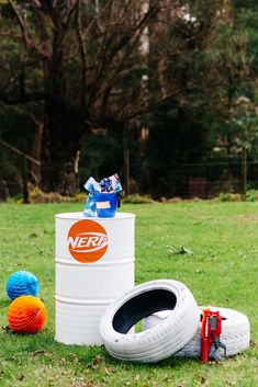 a large white bucket sitting on top of a lush green field next to two balls