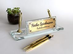 there is a pen that is on top of a glass block with a name plate