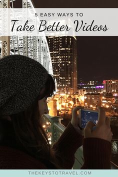 a woman taking a photo with her cell phone in front of the city at night