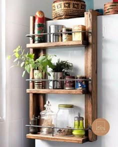 a wooden shelf filled with lots of plants and other items on top of a white wall