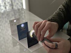 a person using a cell phone on top of a table with a card in front of them