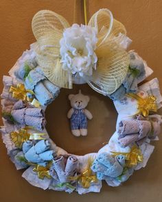 a teddy bear is hanging on the wall next to a wreath made out of diapers