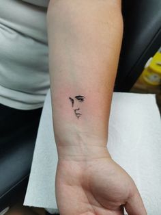 a woman's arm with a small face tattoo on the left side of her wrist