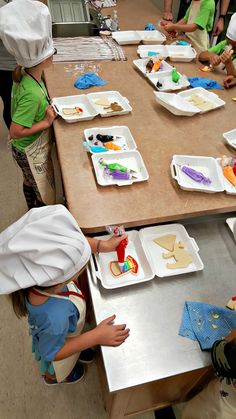 children in chef's hats and aprons are making cookies