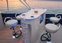 two stools sit on the back of a boat as the sun sets over the water