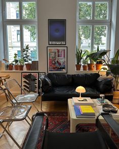 a living room filled with lots of furniture and plants on the windows sills