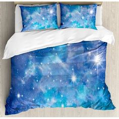 a bed with two pillows on top of it and the covers are covered in colorful clouds