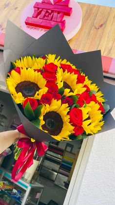 a bouquet of sunflowers and roses is being held by someone's hand