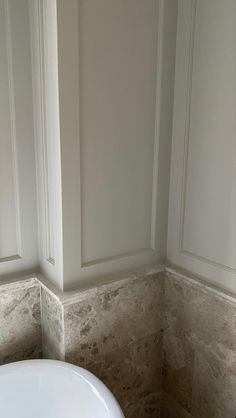 a white sink sitting next to a window in a bathroom with marble walls and floor