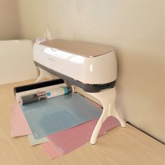 a projector sitting on top of a wooden table next to paper and glue rollers