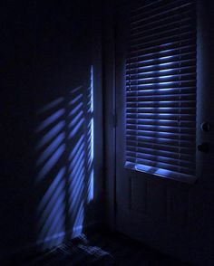 the light is shining through the blinds in the dark room with the door open,