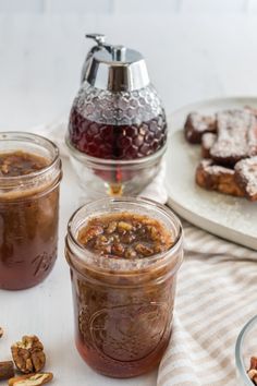 two jars filled with desserts sitting on top of a table next to other food