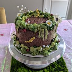 a decorated cake sitting on top of a metal platter next to a green table cloth