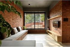 a living room filled with furniture and a large window next to a brick wall covered in plants