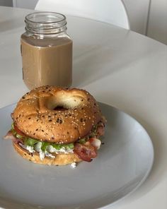 a bagel sandwich on a plate with a jar of peanut butter