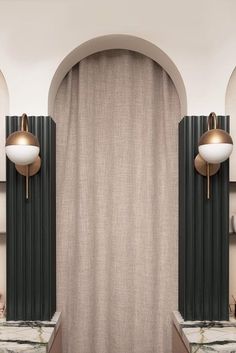 two lamps are on the wall in front of a curtain and some marble counter tops