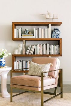 a living room filled with furniture and bookshelves next to a vase full of flowers