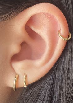 a close up of a person's ear with two gold hoops