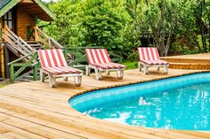 two lawn chairs sitting next to a swimming pool with steps leading up to the deck