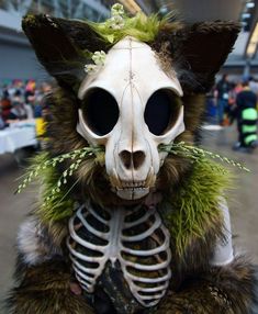 a skeleton cat with flowers on its head and fur coat around it's neck