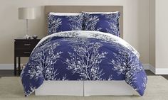 a bed with blue and white comforters in a bedroom next to a night stand