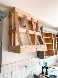 a kitchen with wooden shelves hanging from the ceiling and cabinets on the wall behind it