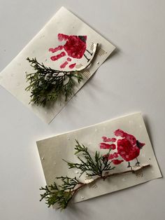 two pieces of paper with red handprints on them, one is made out of branches