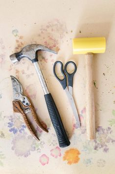 some tools are laying out on a table with paint splotters and flowers around them