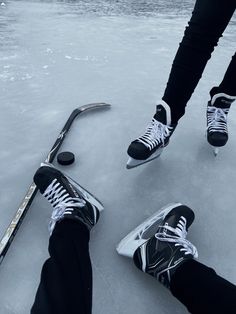 two people are standing on the ice with their feet up and one is holding a hockey stick