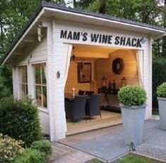 a small white shed with the words mam's wine shack written on it