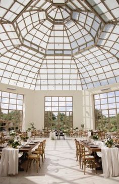 an indoor wedding venue with large windows and tables set up for the guests to eat