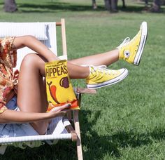 a woman sitting in a lawn chair with her legs crossed and yellow tennis shoes on