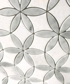 a close up view of a white tile wall with circles and leaves on the surface