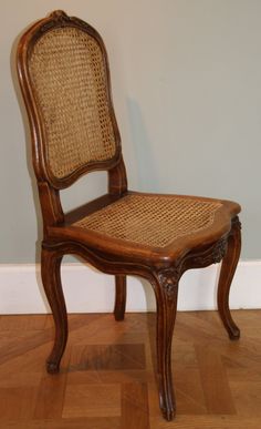 an old wooden chair sitting on top of a hard wood floor next to a wall