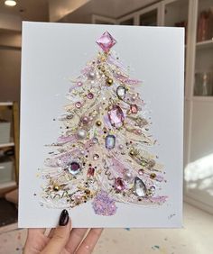 a hand holding up a card with a christmas tree on it